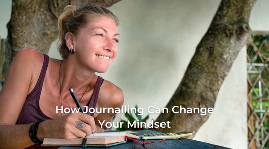 Image of a blonde, tanned lady writing in journal and smiling 